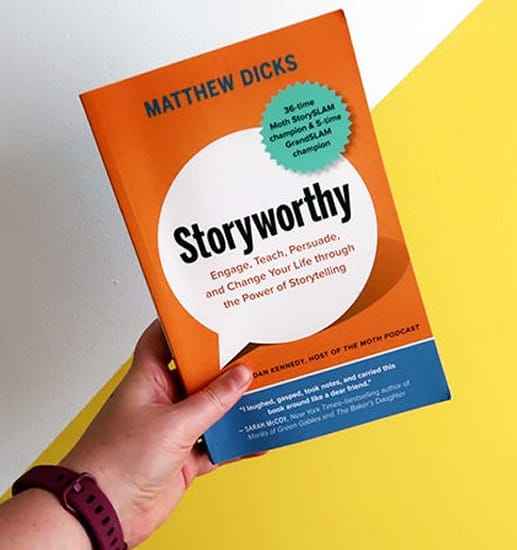 hand holding book cover of storyworthy, orange